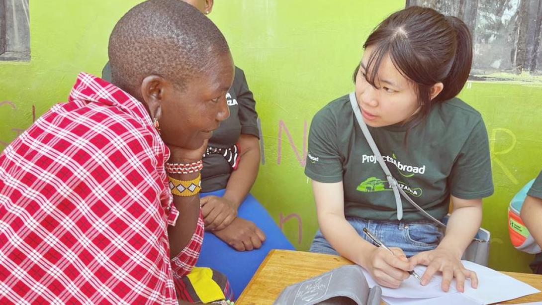 タンザニアの地域コミュニティでヘルススクリーニングを手伝う高校生医療ボランティア